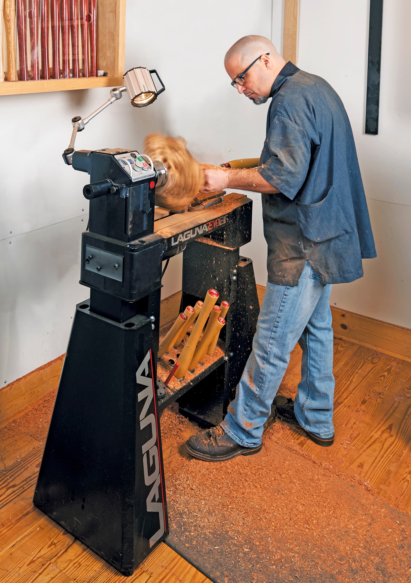 Woodturner making live-edge bowl on midi-lathe in shop setting.